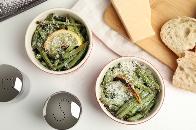 Delicious baked green beans served on white table, flat lay