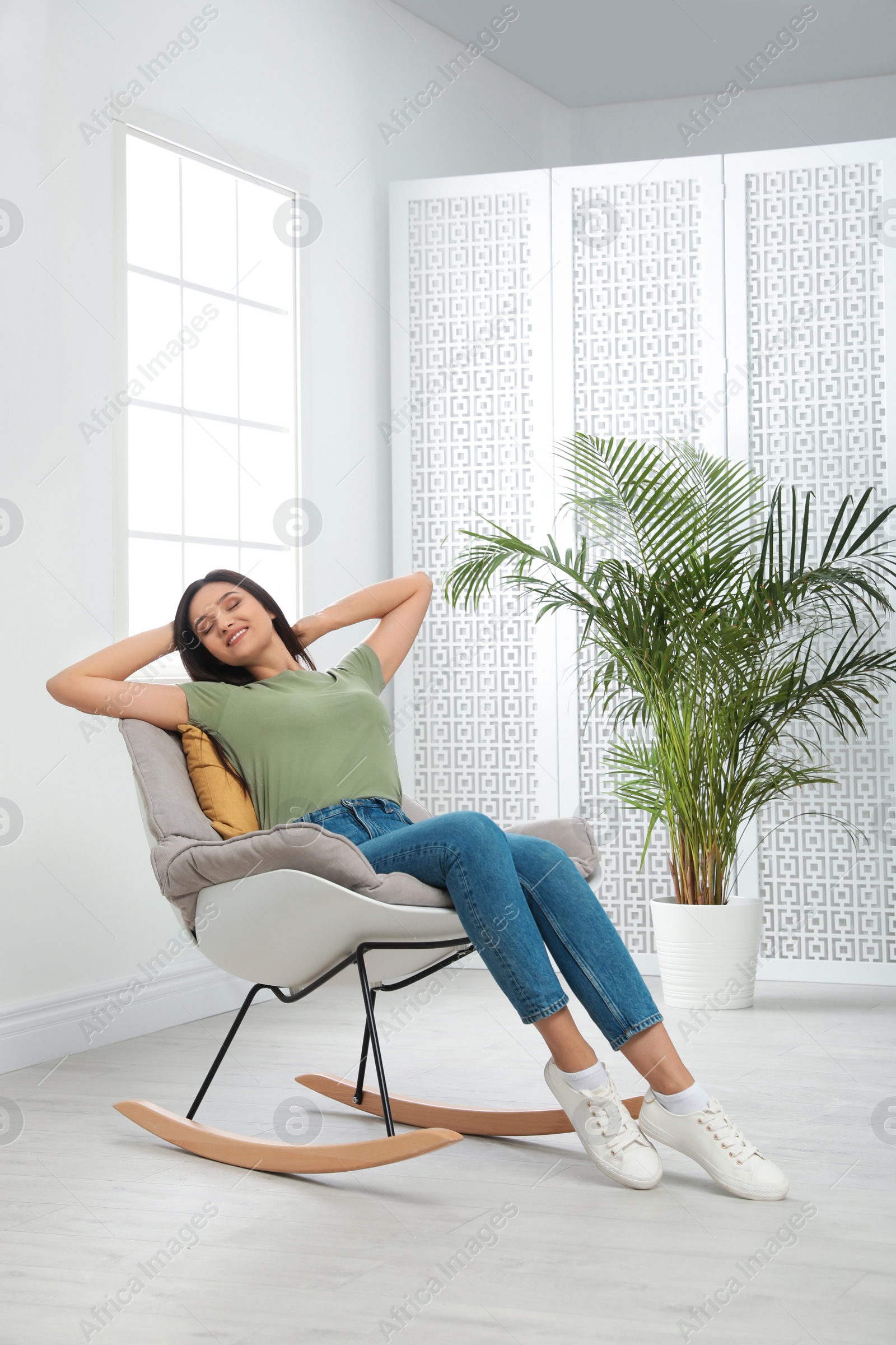 Photo of Young woman relaxing in rocking chair at home