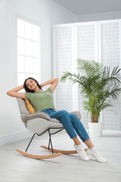 Young woman relaxing in rocking chair at home