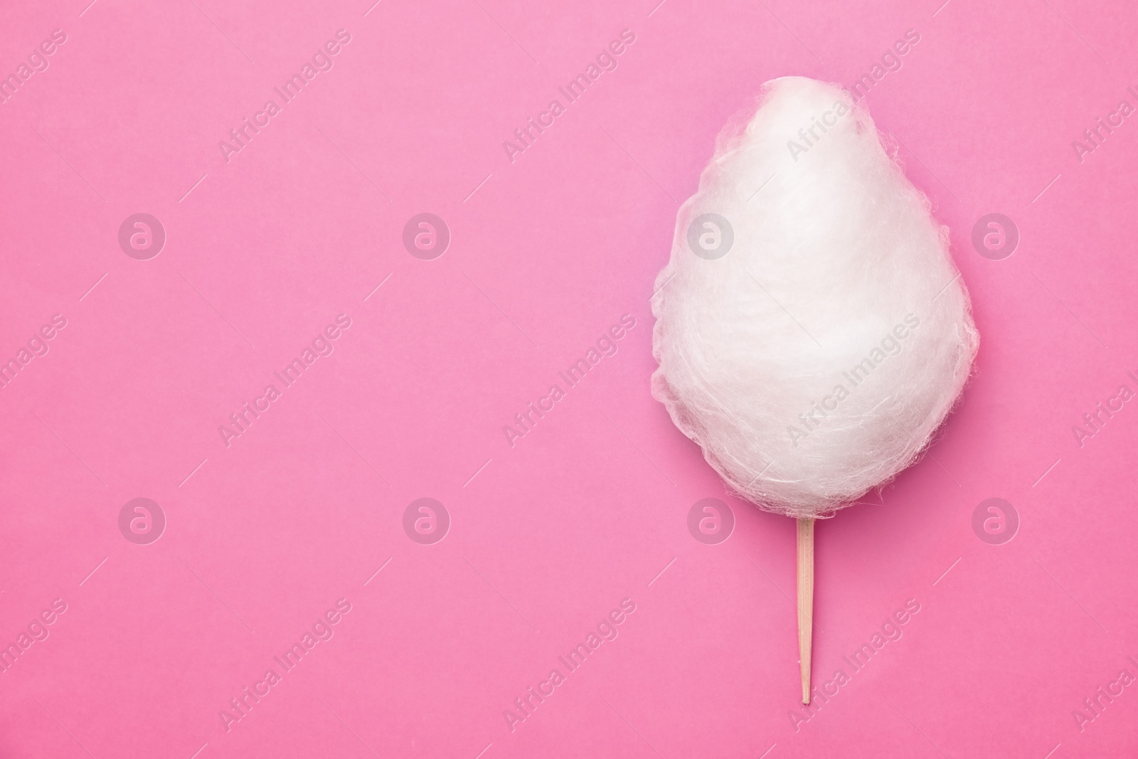 Photo of Stick with yummy cotton candy on color background, top view. Space for text