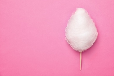 Photo of Stick with yummy cotton candy on color background, top view. Space for text