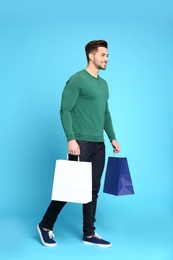 Photo of Full length portrait of young man with paper bags on blue background