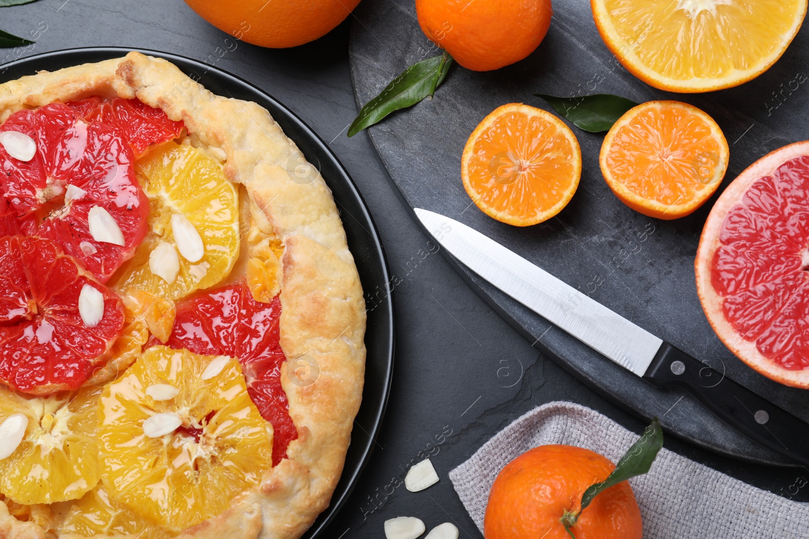 Photo of Tasty galette with citrus fruits served on grey table, flat lay