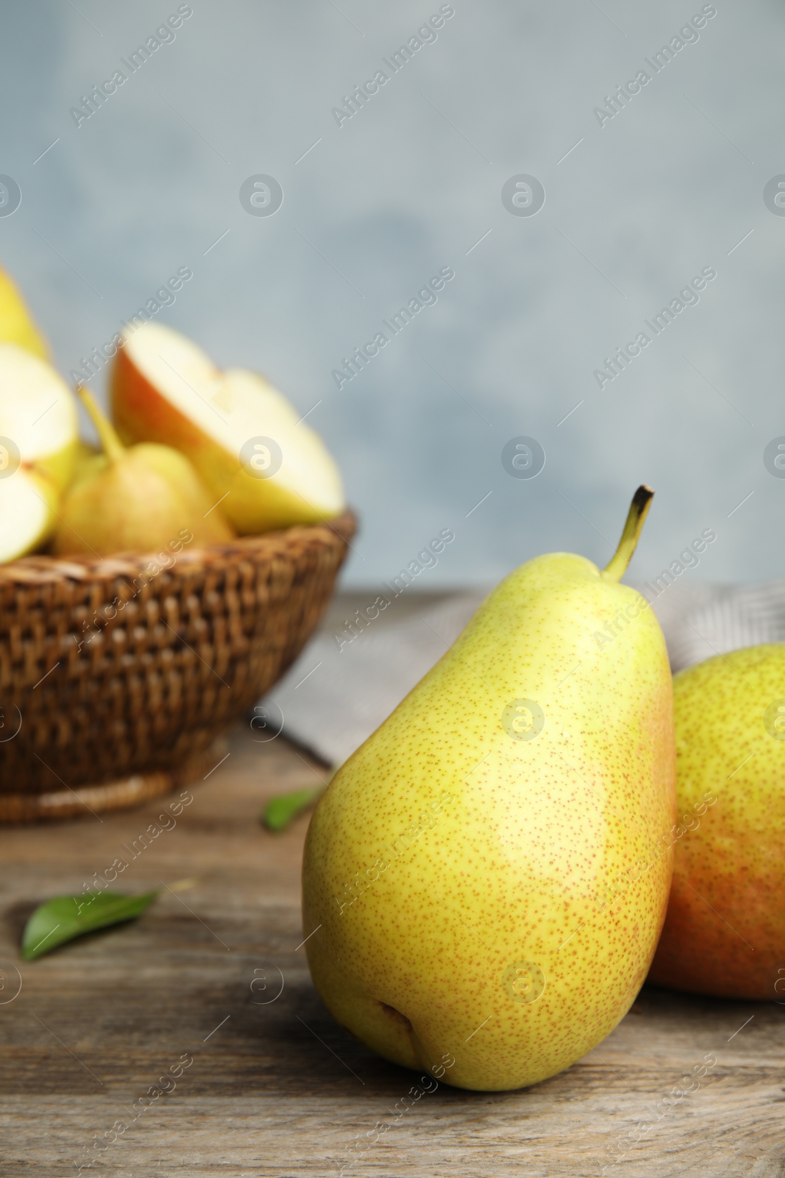 Photo of Ripe juicy pears on brown wooden table against blue background. Space for text