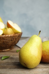 Ripe juicy pears on brown wooden table against blue background. Space for text