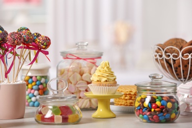 Photo of Candy bar with different sweets on white table against blurred background