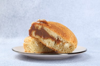 Photo of Supreme croissant with chocolate paste and nuts on grey table, closeup. Tasty puff pastry