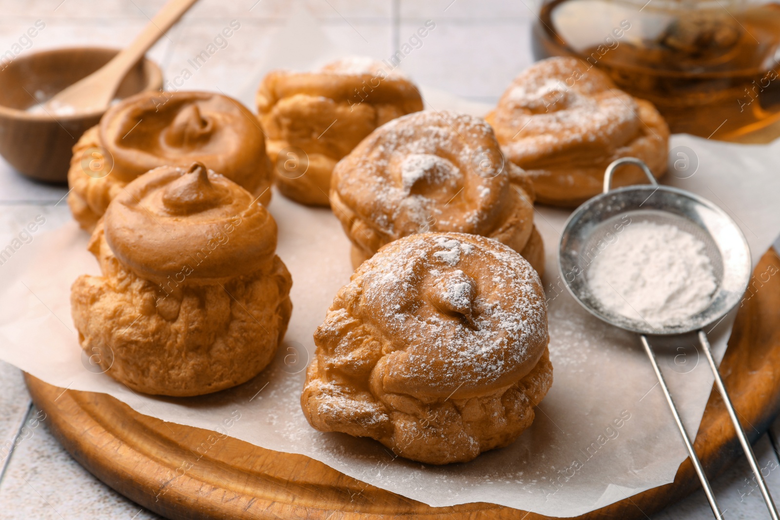 Photo of Delicious profiteroles with powdered sugar on white table, closeup