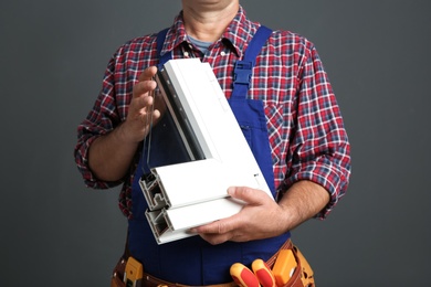 Photo of Installation worker with sample of modern window profile on gray background