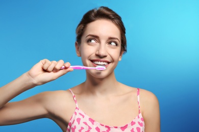 Portrait of young woman with toothbrush on color background