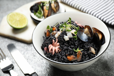 Photo of Delicious black risotto with seafood in bowl on table