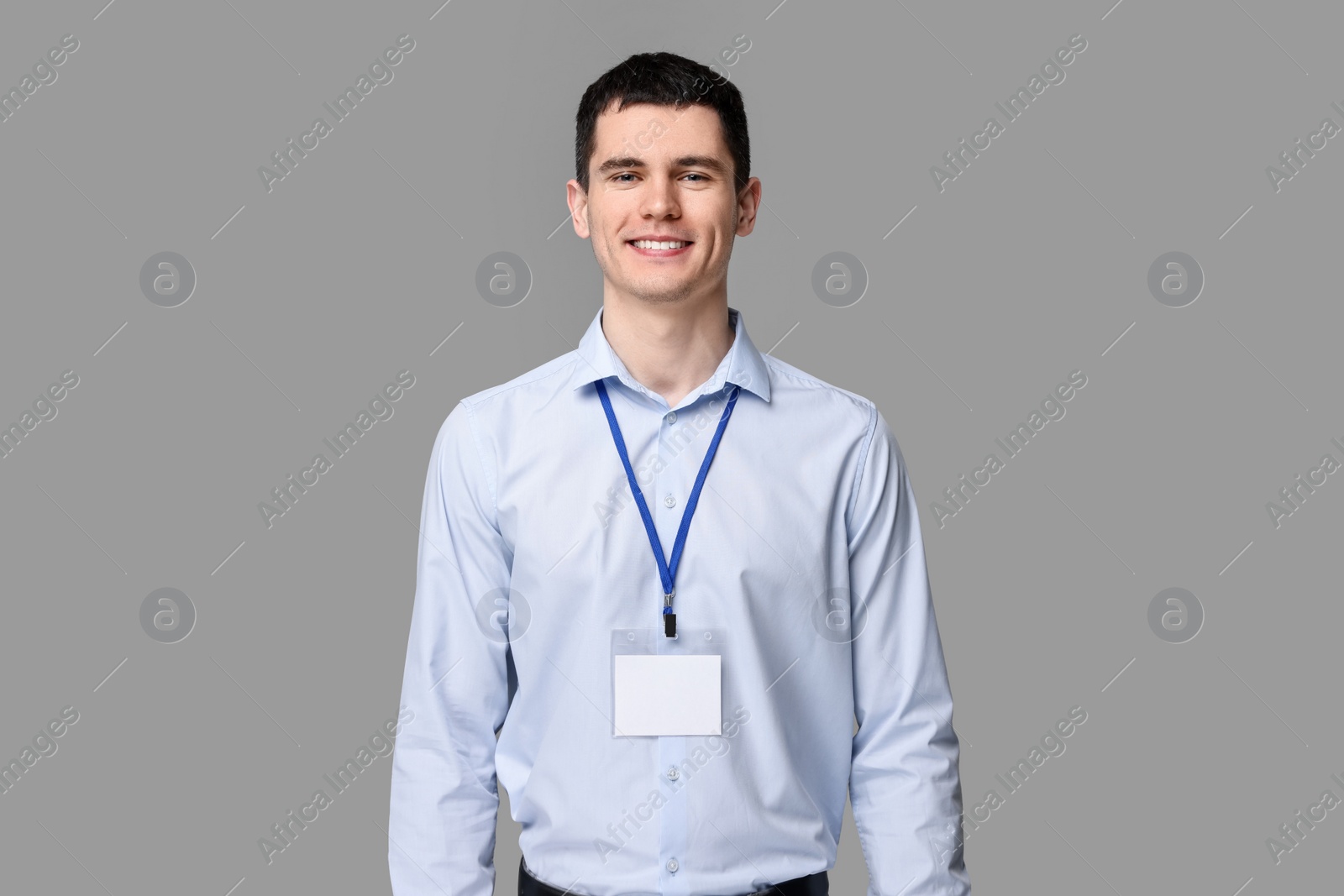 Photo of Smiling man with empty badge on grey background