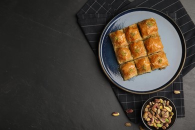 Photo of Delicious sweet baklava with pistachios on black table, flat lay. Space for text