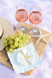 Glasses with rose wine and snacks on picnic blanket