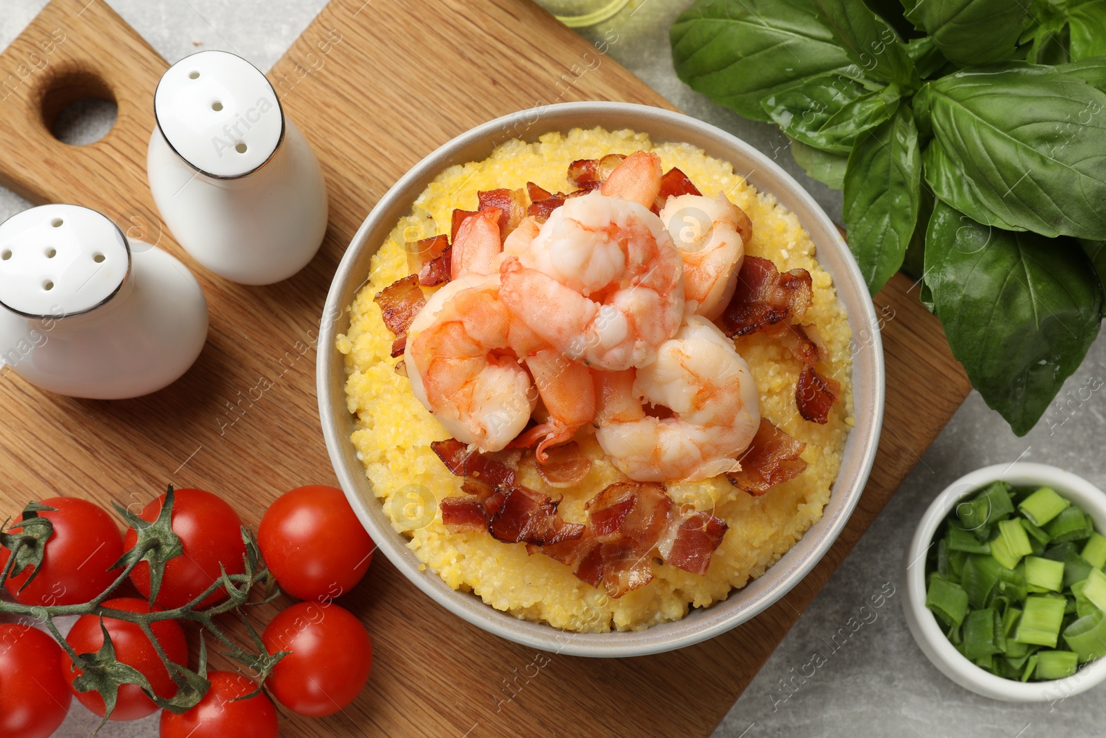 Photo of Fresh tasty shrimps, bacon and grits in bowl on table, flat lay