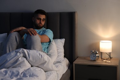 Frustrated man suffering from insomnia on bed