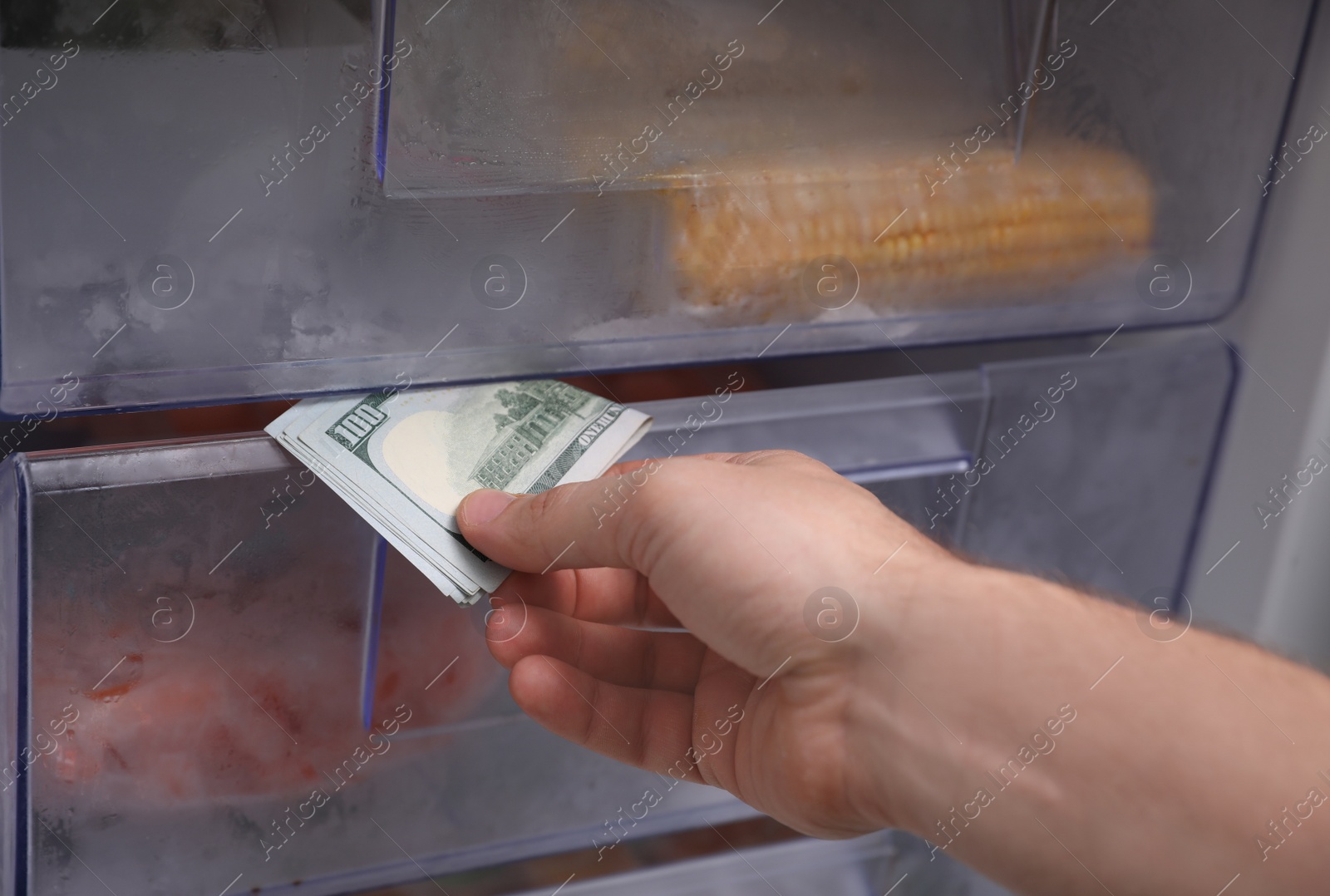 Photo of Man hiding money in refrigerator, closeup. Financial savings