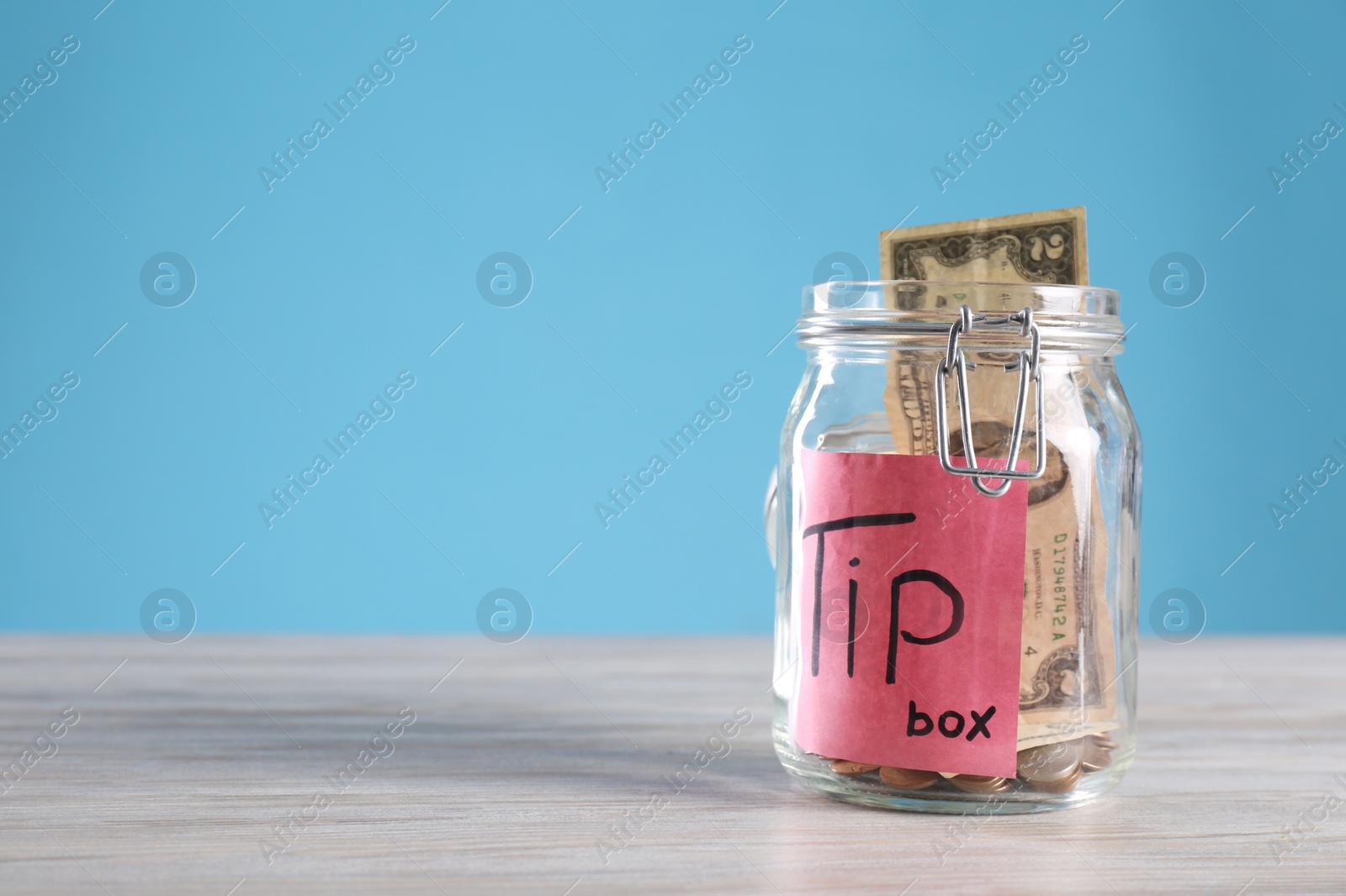 Photo of Glass jar with tips on wooden table, closeup. Space for text