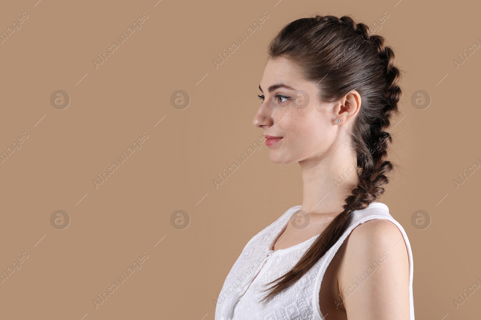 Photo of Woman with braided hair on light brown background. Space for text