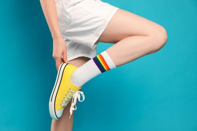 Photo of Woman posing in yellow classic old school sneakers on light blue background, closeup