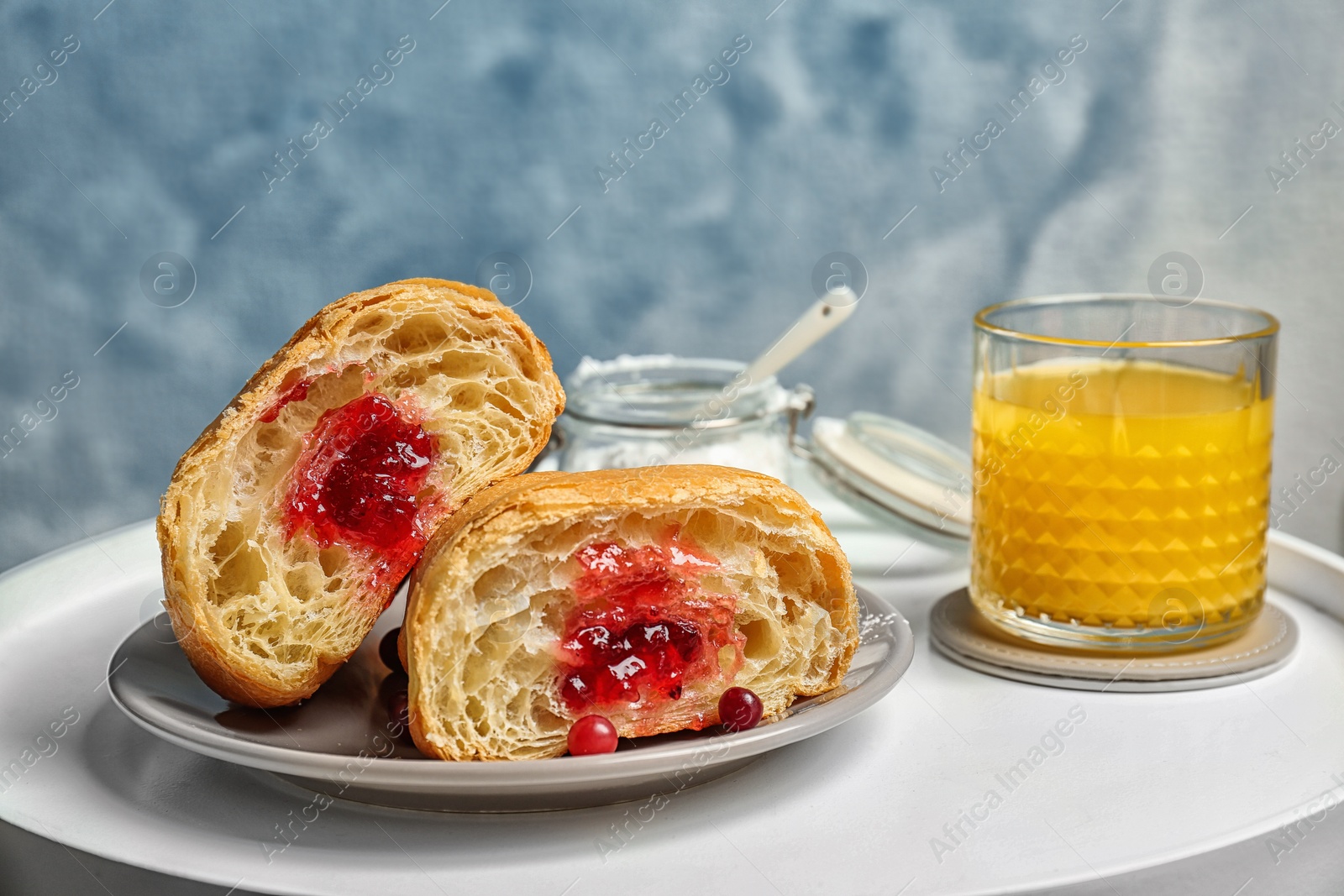 Photo of Tasty croissant with jam and glass of juice on table