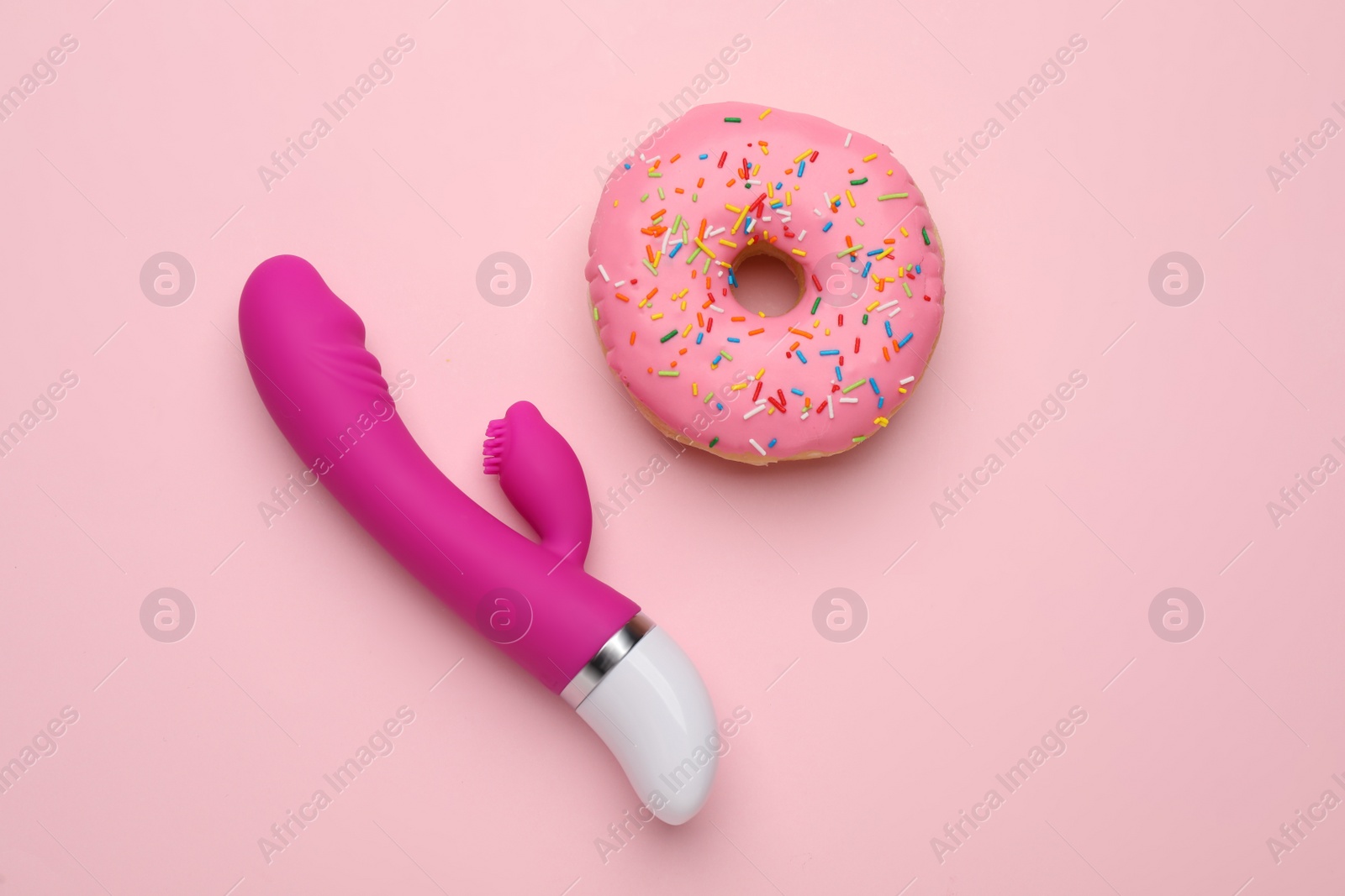 Photo of Vaginal vibrator and donut on pink background, flat lay. Sex toy