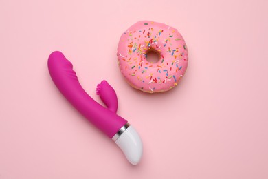 Photo of Vaginal vibrator and donut on pink background, flat lay. Sex toy