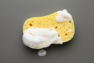 Photo of Yellow sponge with foam on grey background, top view