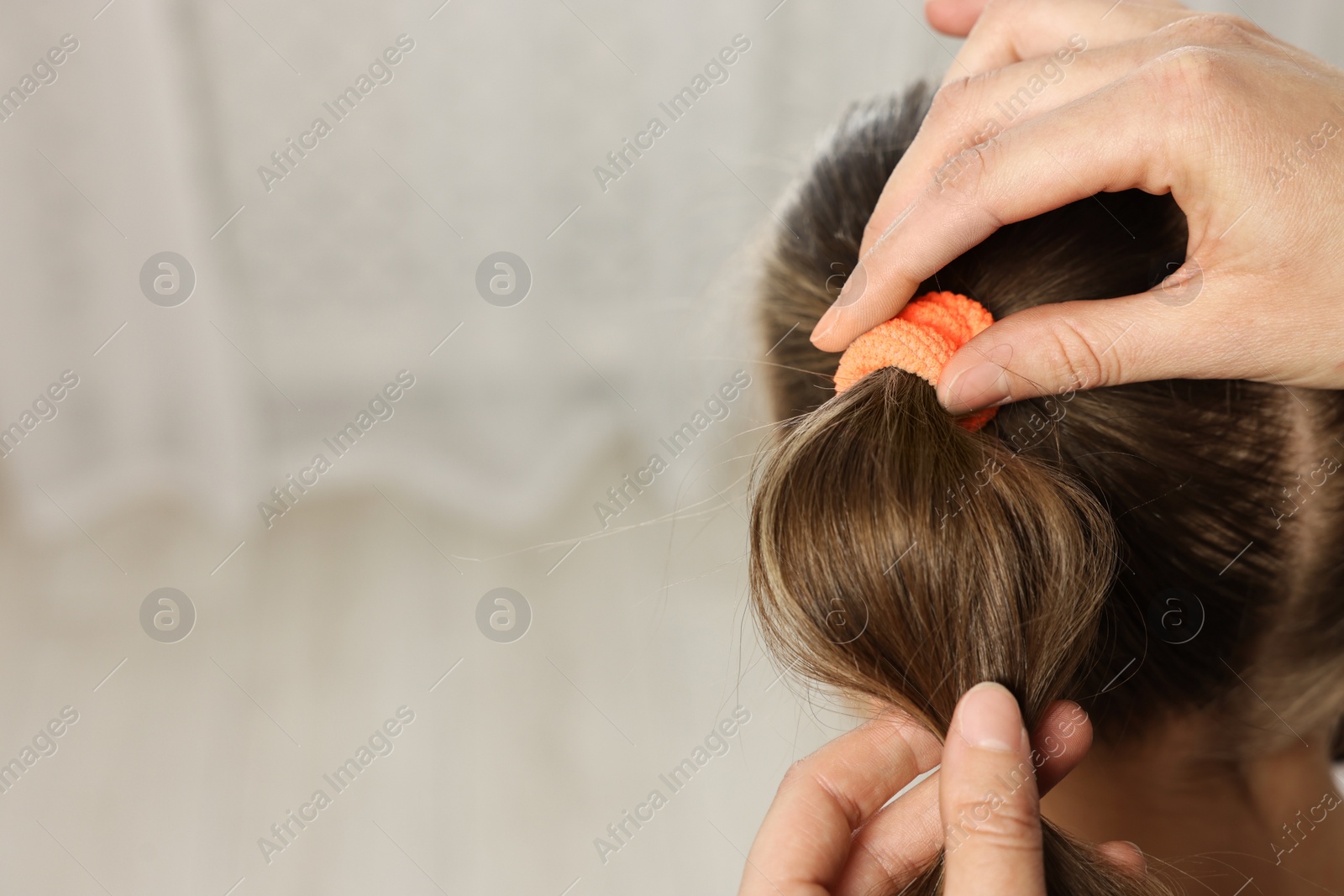 Photo of Professional stylist braiding girl's hair indoors, closeup