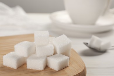Photo of Refined sugar cubes with wooden board on table, closeup