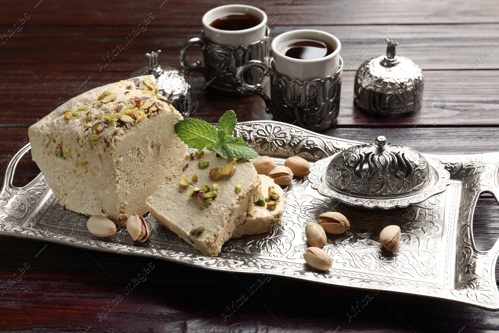 Photo of Tasty halva with pistachios and mint served on wooden table