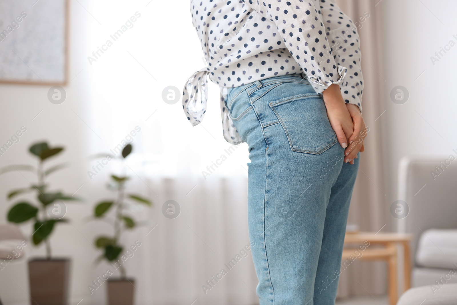 Photo of Young woman suffering from hemorrhoid at home, closeup. Space for text