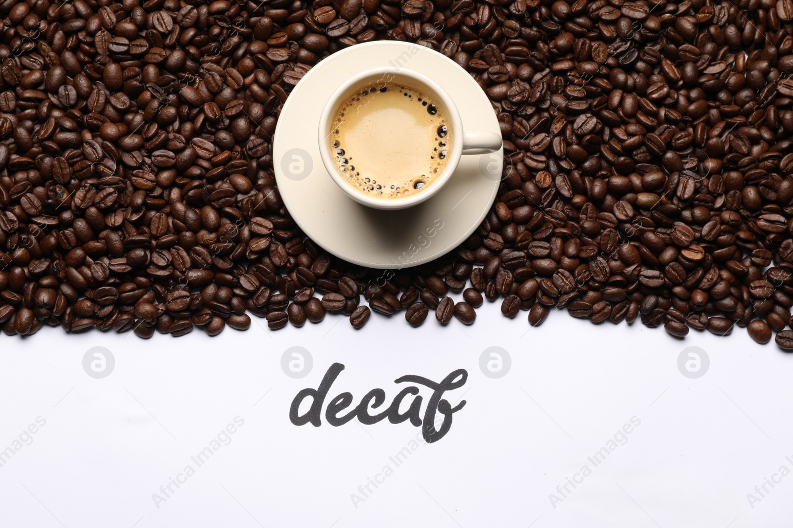 Photo of Word Decaf, cup of coffee and beans on white background, flat lay