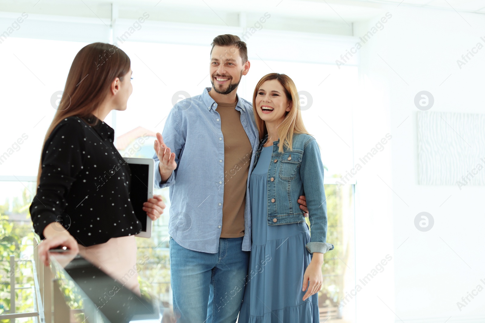 Photo of Female real estate agent showing new house to couple, indoors