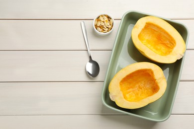 Photo of Halves of fresh spaghetti squash in baking dish on white wooden table, flat lay with space for text. Cooking at home