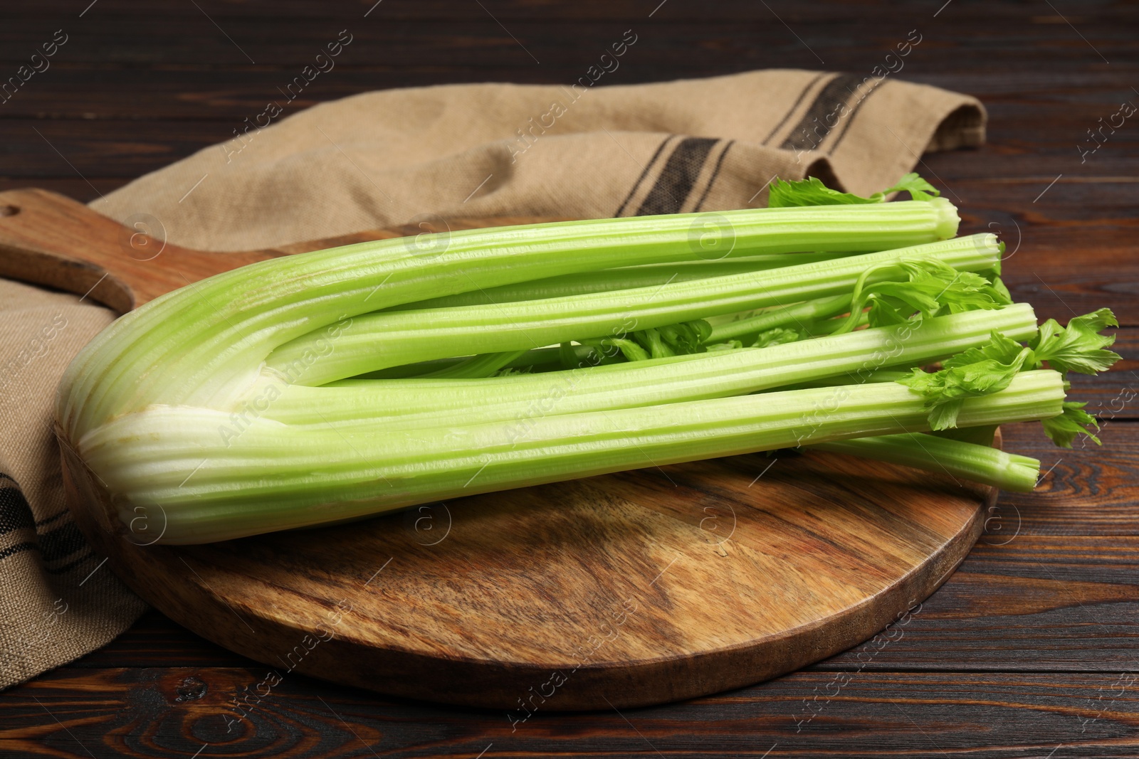 Photo of Board with fresh cut celery bunch on wooden table, closeup