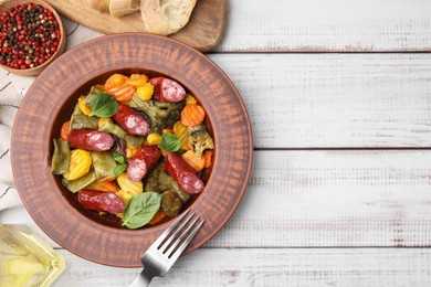 Photo of Delicious sausage and baked vegetables served on white wooden table, flat lay. Space for text