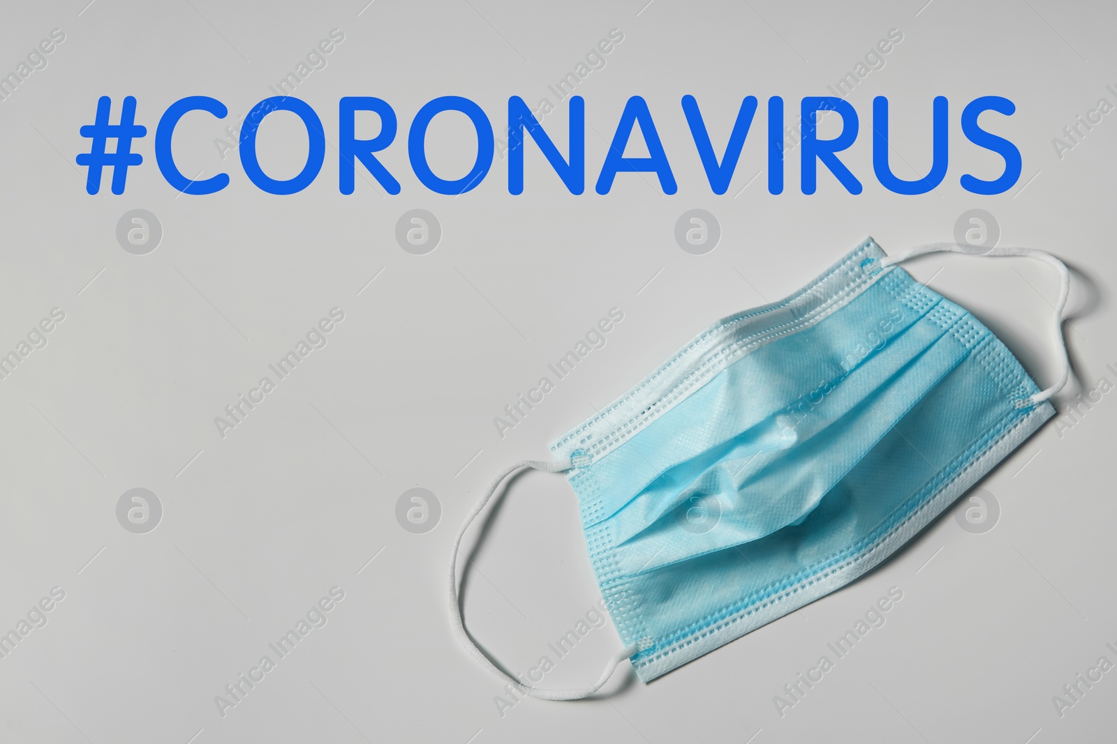 Image of Hashtag Coronavirus and medical mask on light background, top view