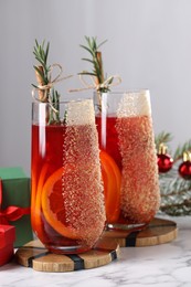Photo of Christmas Sangria cocktail in glasses and festive decor on white marble table