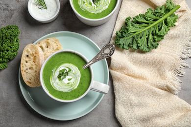 Photo of Tasty kale soup served on grey table, flat lay