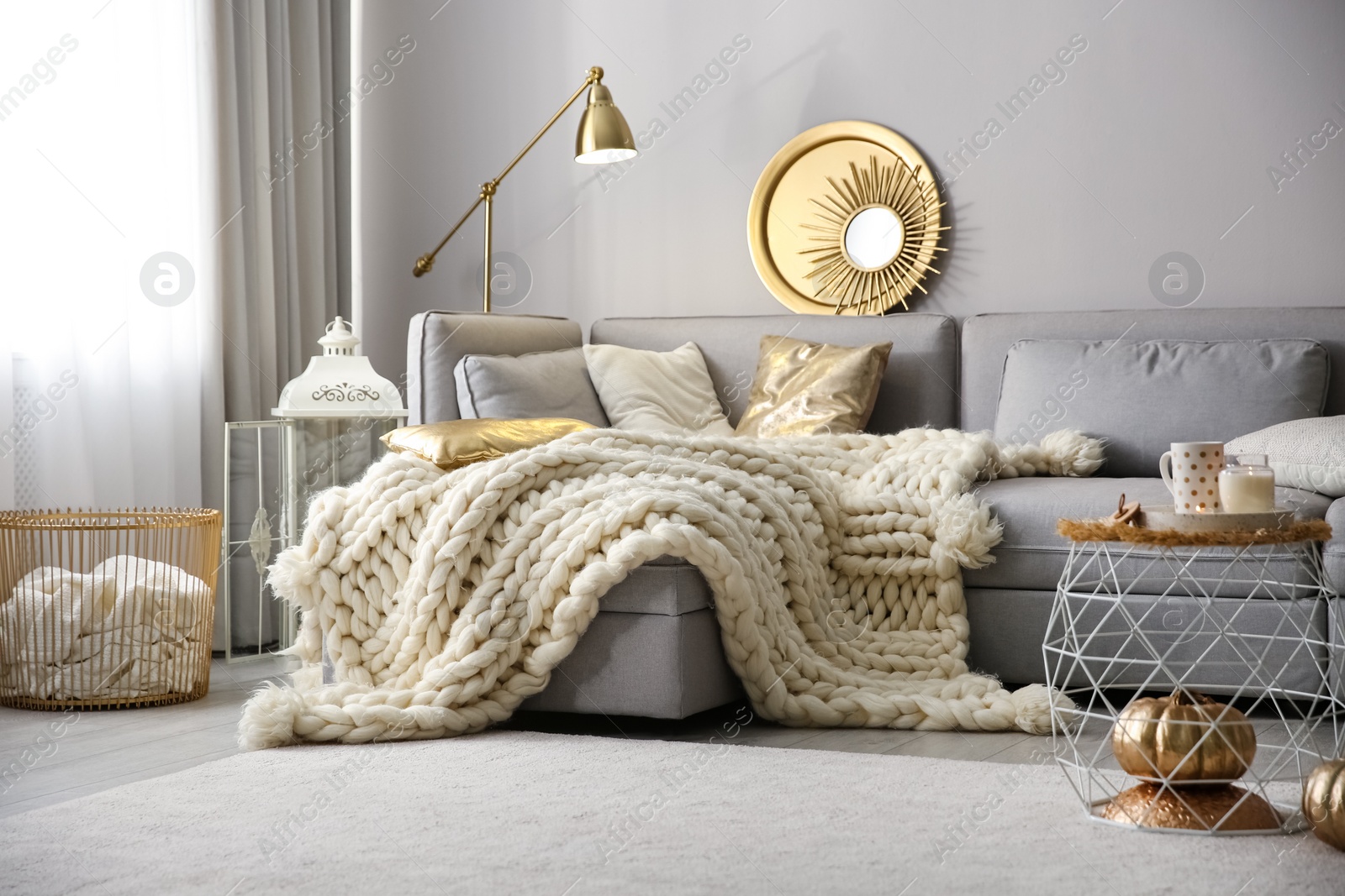 Photo of Cozy living room interior with knitted blanket on comfortable sofa