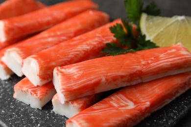 Photo of Fresh crab sticks with lemon on table, closeup