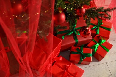 Photo of Beautifully wrapped gift boxes under Christmas tree indoors, above view