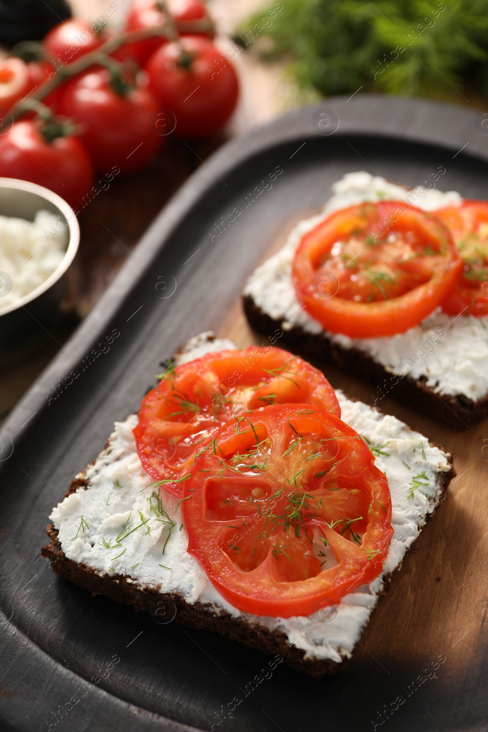 Photo of Delicious ricotta bruschettas with sliced tomatoes and dill on wooden table, closeup