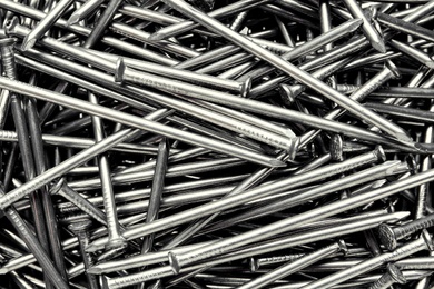 Photo of Pile of metal nails as background, closeup