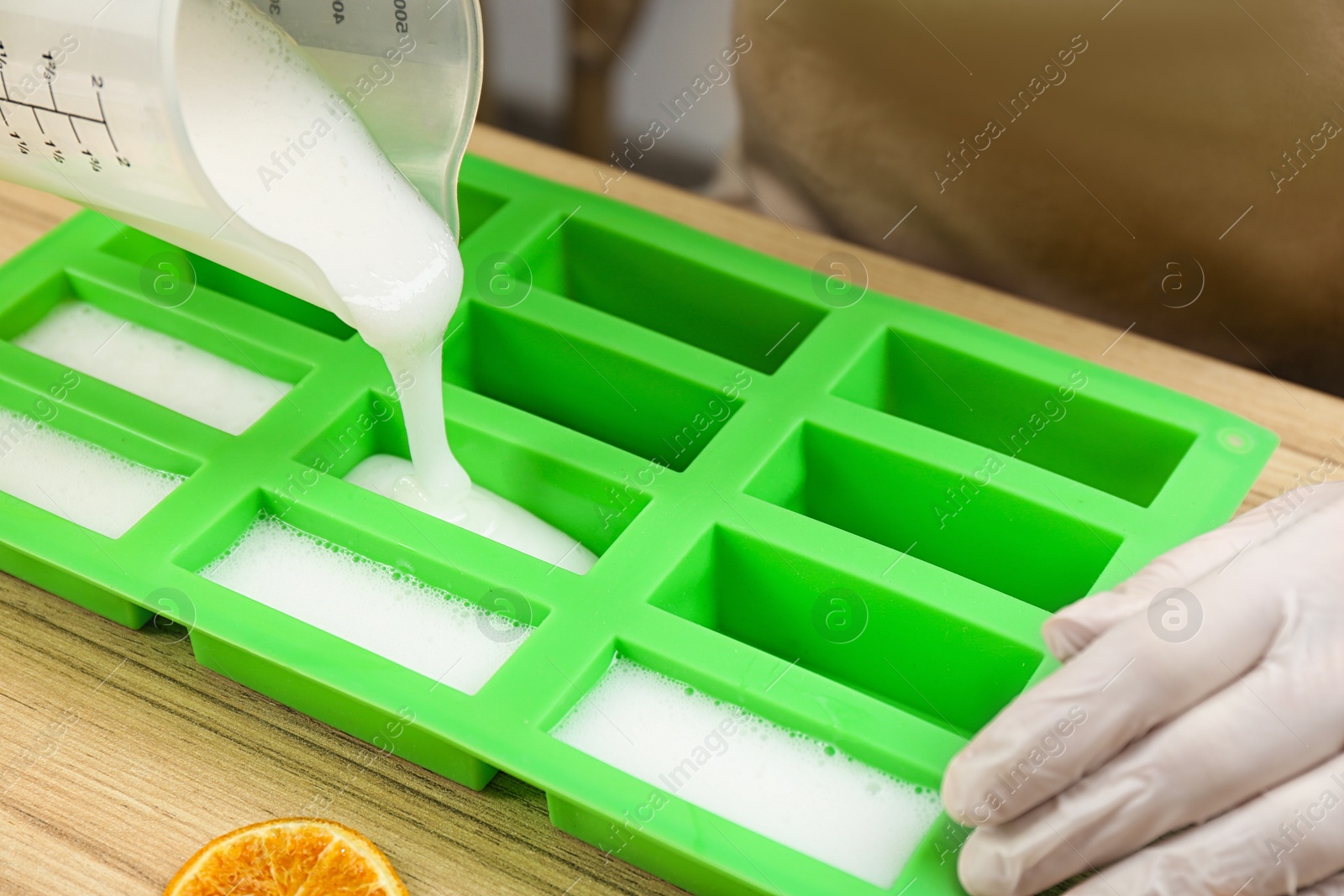 Photo of Woman making natural handmade soap at wooden table, closeup