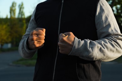 Photo of Angry man with clenched fists outdoors, closeup