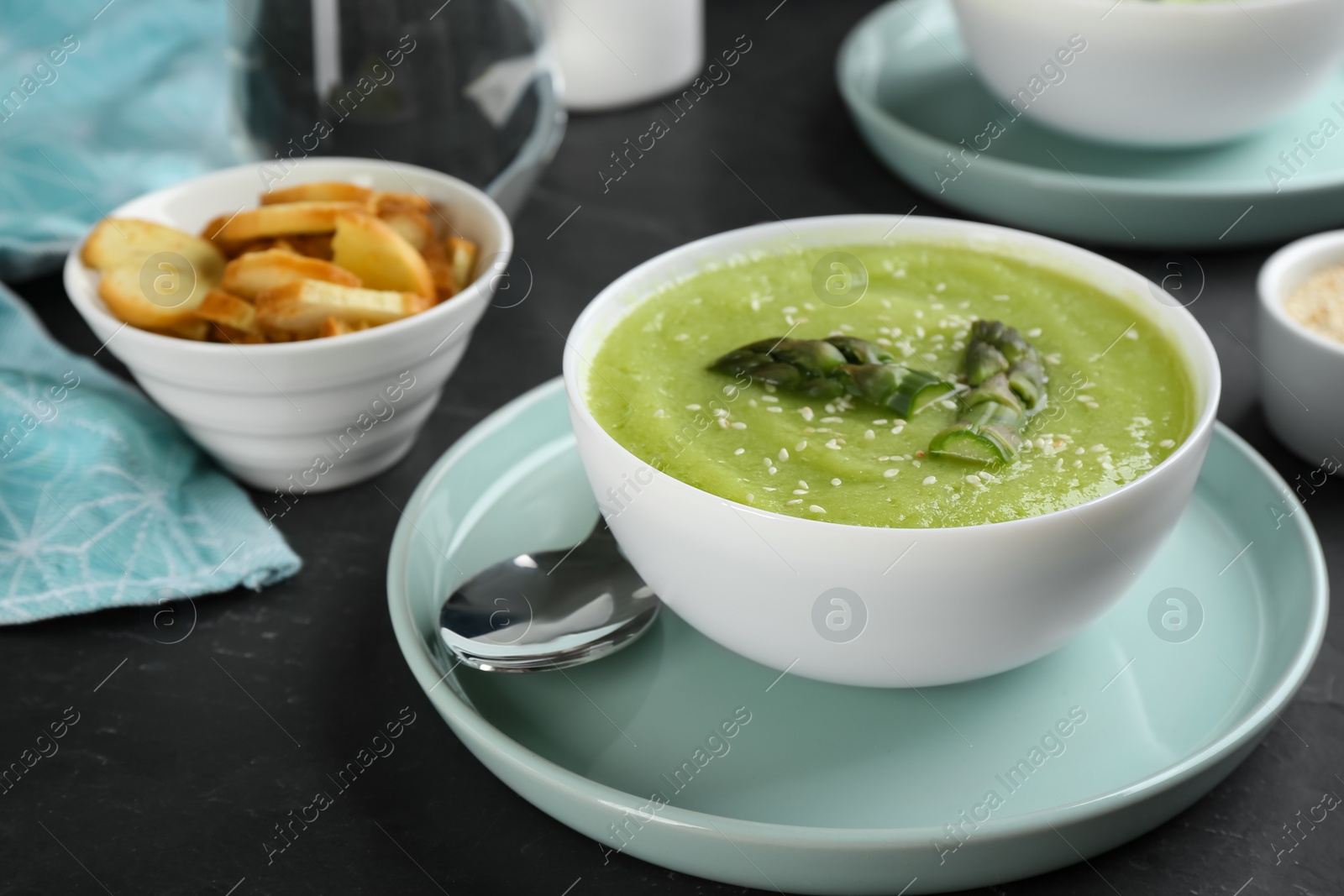 Photo of Delicious asparagus soup served on black table