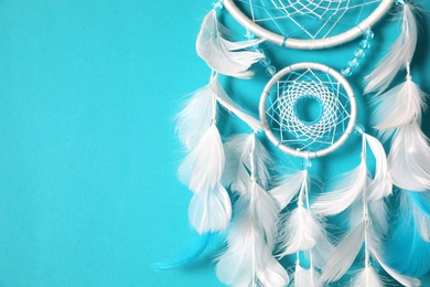 Photo of Beautiful dream catcher hanging on light blue background, closeup. Space for text