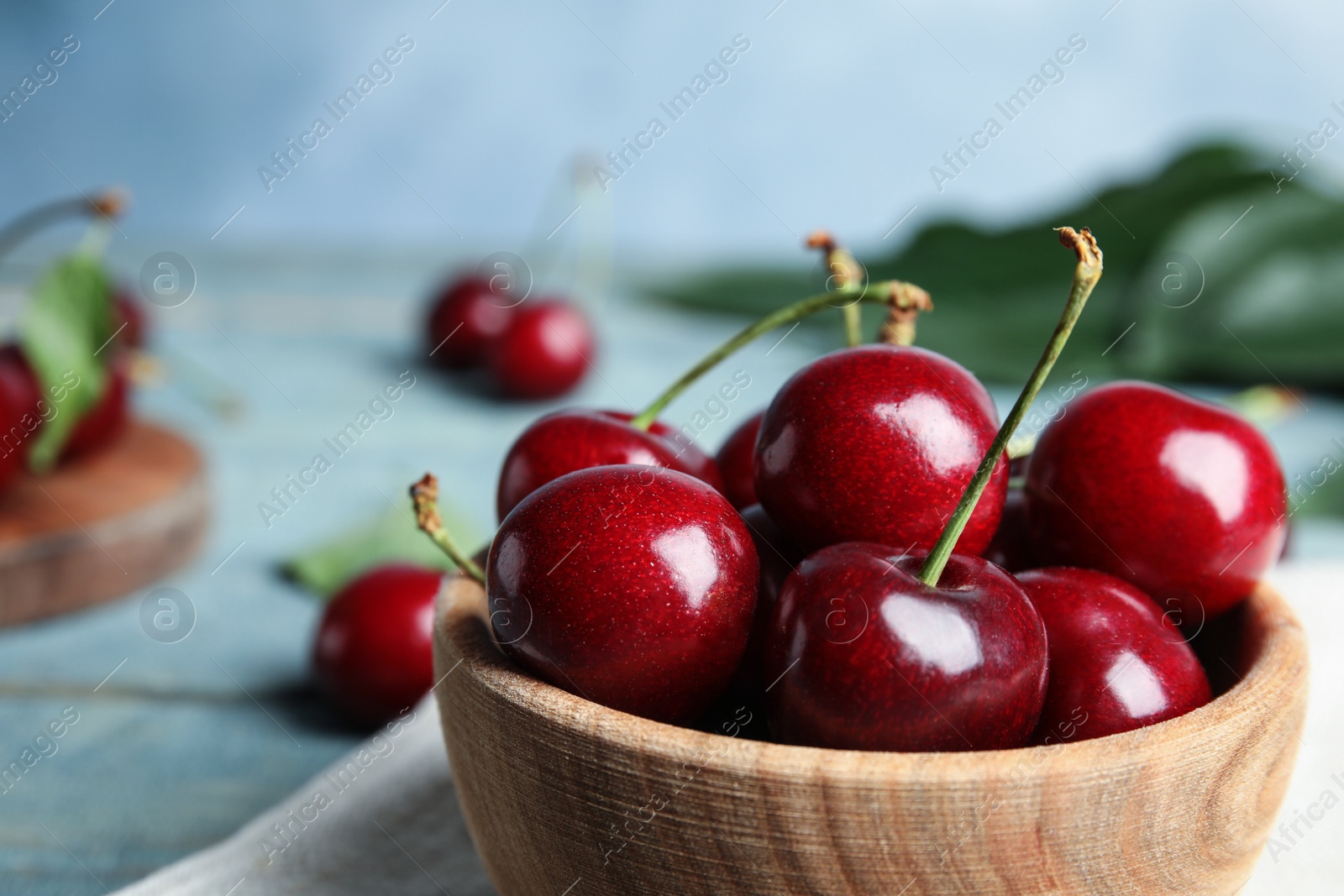 Photo of Wooden bowl with ripe sweet cherries on table, closeup. Space for text